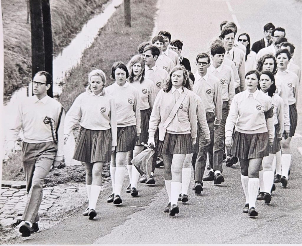 Historische zwart-witfoto van een groep jonge wandelaars in uniform tijdens een mars.