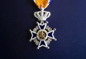 Medaille van de Orde van Oranje-Nassau met blauw-wit-oranje lint op een donkerblauwe achtergrond.