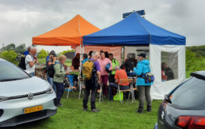 Groep wandelaars bij een verzorgingspost met tenten tijdens een evenement.